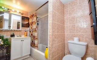 full bathroom featuring tile walls, toilet, and shower / bathtub combination with curtain