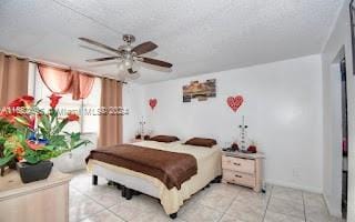 bedroom featuring ceiling fan, light tile patterned floors, and a textured ceiling