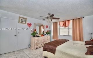 bedroom with a textured ceiling, ceiling fan, and light tile patterned flooring