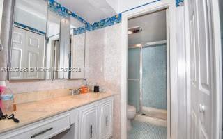 bathroom featuring an enclosed shower, toilet, and vanity