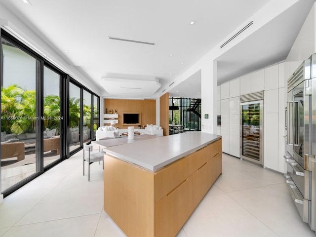 kitchen featuring white cabinetry, light tile patterned floors, wine cooler, a center island, and light brown cabinets