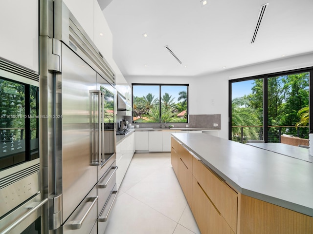 kitchen featuring light brown cabinetry, plenty of natural light, white cabinetry, and light tile patterned flooring