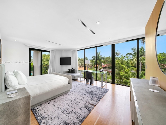 bedroom with expansive windows and light hardwood / wood-style floors