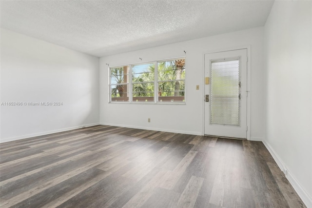 empty room featuring a textured ceiling and dark hardwood / wood-style flooring