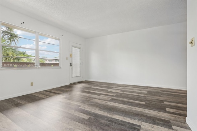 empty room featuring a textured ceiling and dark hardwood / wood-style flooring