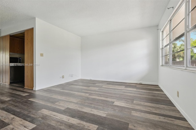 empty room featuring a textured ceiling and dark hardwood / wood-style flooring