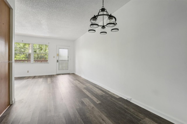 unfurnished room with a textured ceiling, dark hardwood / wood-style flooring, and a notable chandelier