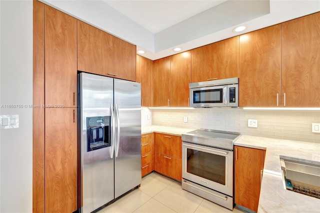 315 NE 3rd Ave Unit 1505, Fort Lauderdale, FL 33301 - kitchen with stainless steel appliances, brown cabinetry, backsplash, light tile patterned floors, and recessed lighting
