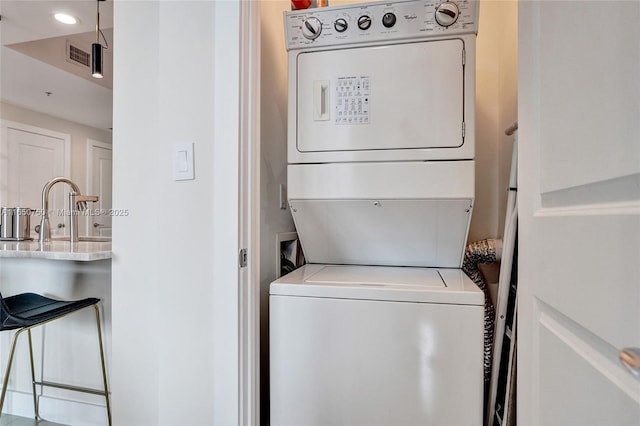 washroom featuring laundry area, visible vents, stacked washer / dryer, a sink, and recessed lighting