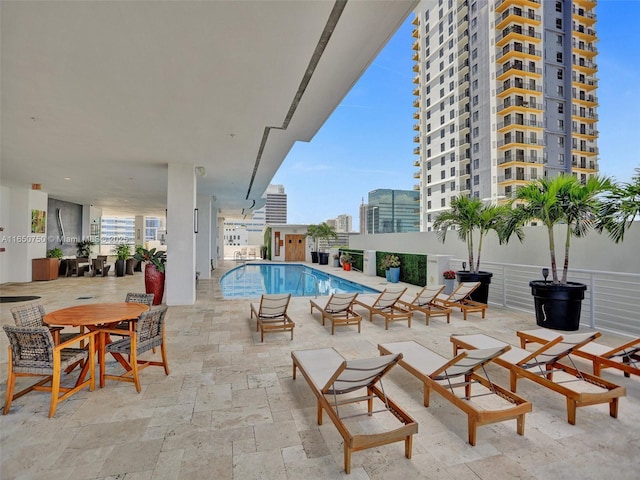 community pool with a patio area and a city view