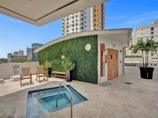 view of pool with a city view, a patio, and a hot tub