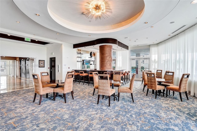 dining area featuring carpet, a raised ceiling, visible vents, and decorative columns