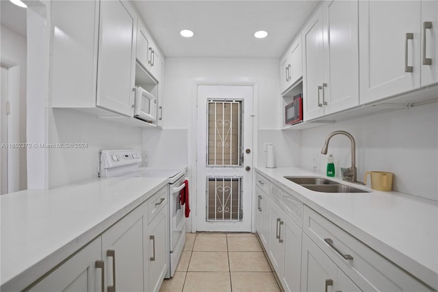 kitchen featuring white cabinets, white appliances, light tile patterned flooring, and sink