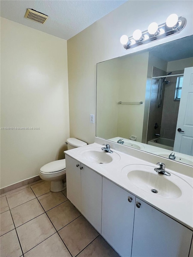 full bathroom featuring tiled shower / bath, tile patterned flooring, vanity, toilet, and a textured ceiling