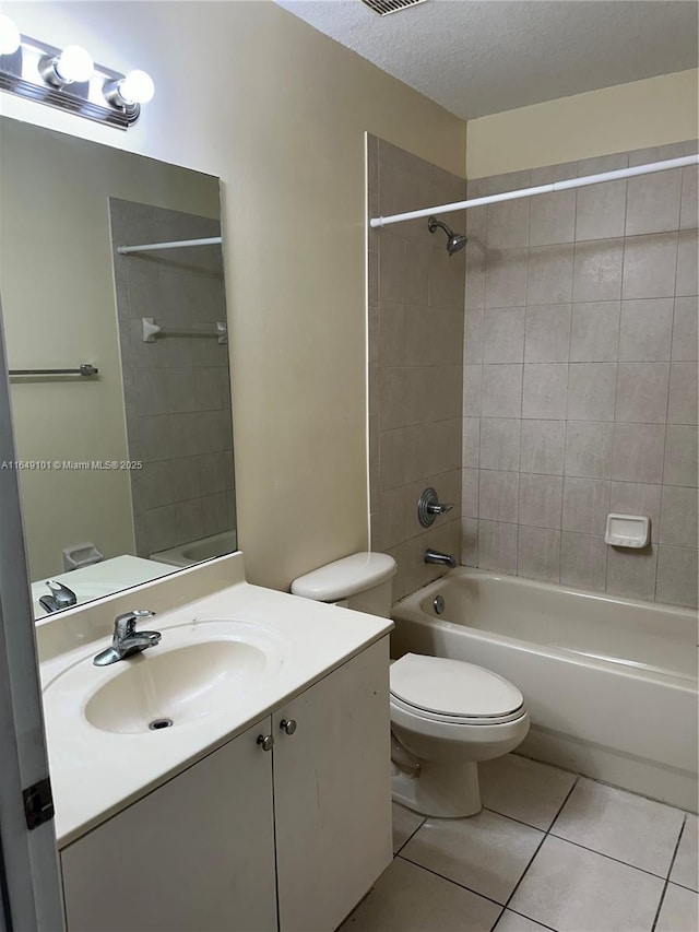 full bathroom featuring tiled shower / bath, tile patterned flooring, vanity, toilet, and a textured ceiling