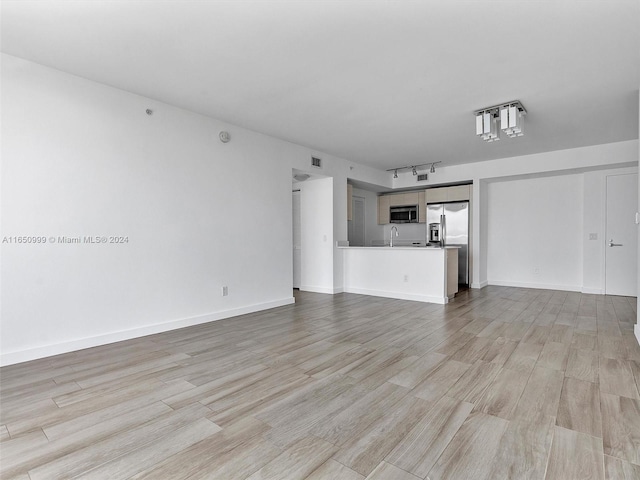 unfurnished living room featuring sink and light hardwood / wood-style flooring