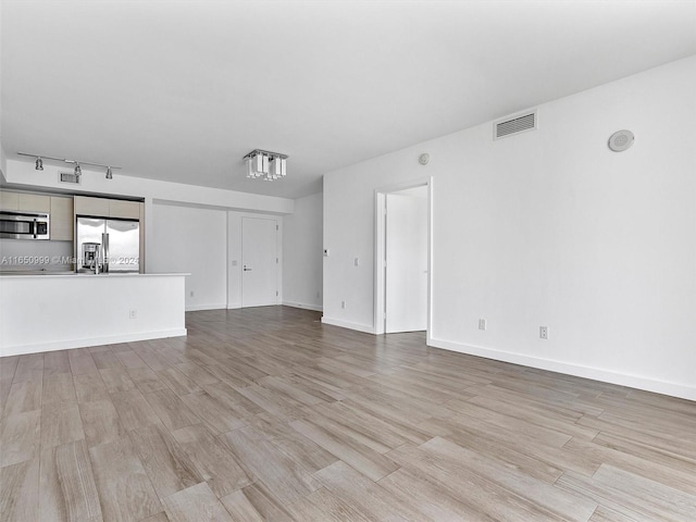 unfurnished living room with light hardwood / wood-style floors and rail lighting