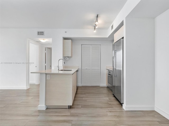 kitchen with stainless steel fridge, light hardwood / wood-style floors, kitchen peninsula, and sink