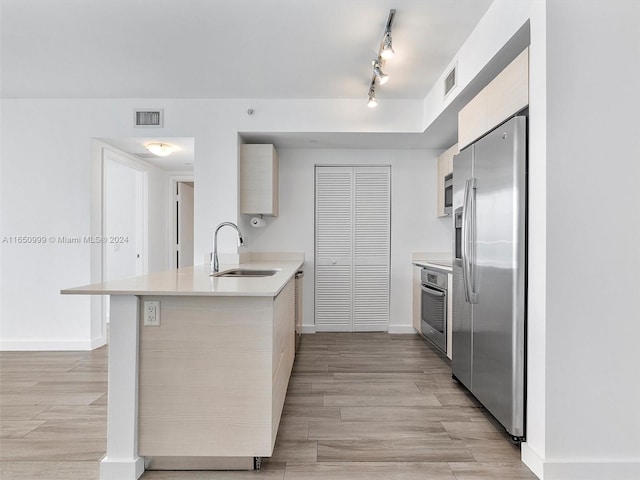 kitchen featuring sink, kitchen peninsula, light hardwood / wood-style flooring, stainless steel appliances, and a breakfast bar area