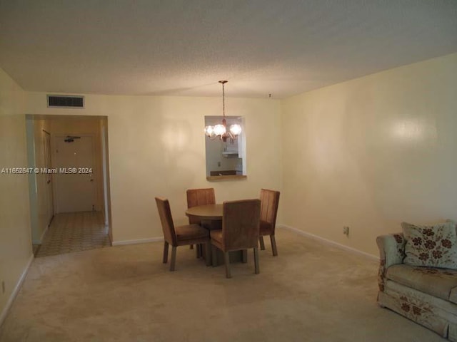 carpeted dining room featuring an inviting chandelier and a textured ceiling