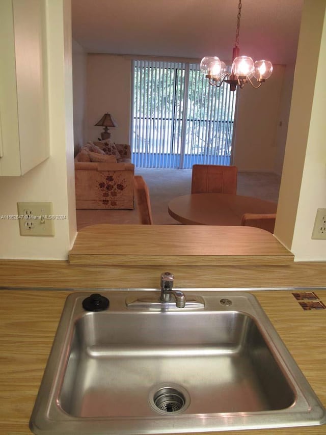 kitchen featuring pendant lighting, an inviting chandelier, sink, and white cabinets