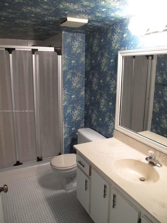 bathroom with tile patterned flooring, toilet, an enclosed shower, and vanity