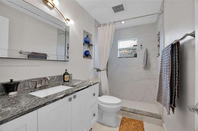 bathroom with tile patterned flooring, walk in shower, toilet, and vanity