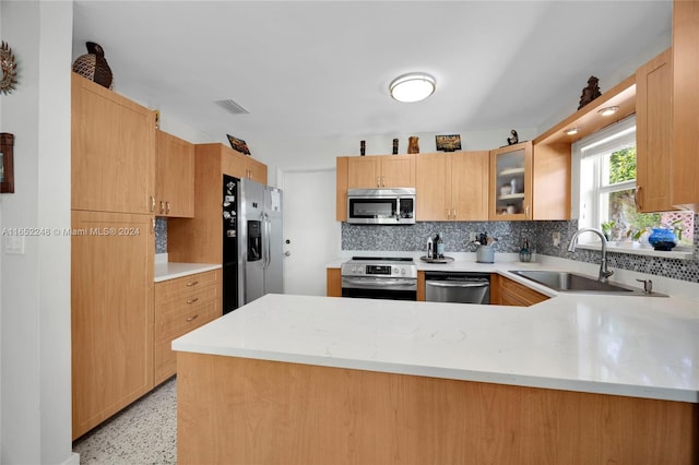 kitchen featuring backsplash, stainless steel appliances, sink, light brown cabinets, and kitchen peninsula