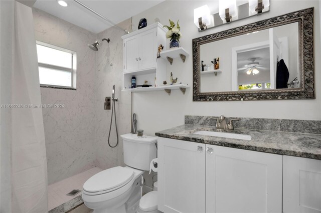 bathroom featuring vanity, ceiling fan, toilet, and a tile shower