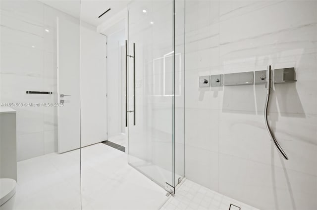 bathroom featuring a shower with door and toilet