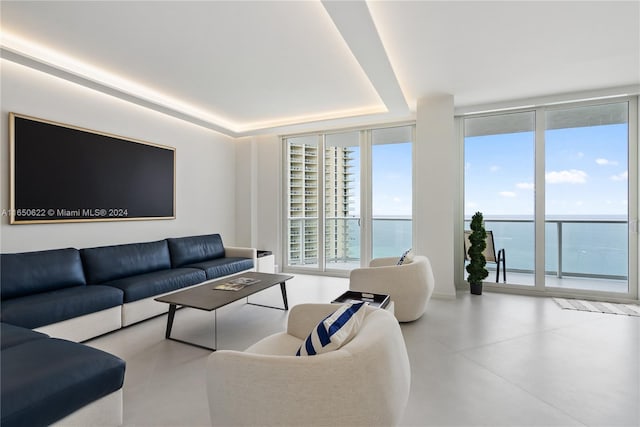 living room with a water view, a wall of windows, and a tray ceiling