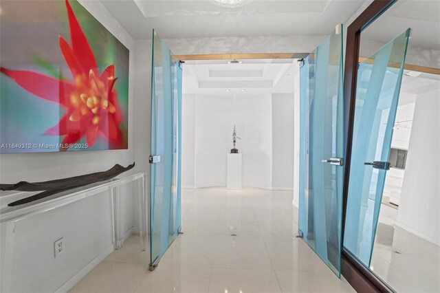 interior space with a tray ceiling and tile patterned floors