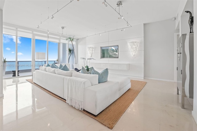 living area featuring a wall of windows, a water view, and baseboards