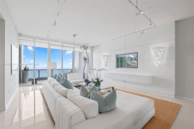 living room with rail lighting, floor to ceiling windows, and a water view