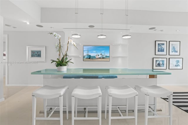 bar featuring baseboards, pendant lighting, and indoor bar