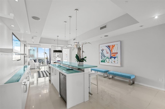 kitchen with a spacious island, visible vents, white cabinetry, a raised ceiling, and pendant lighting