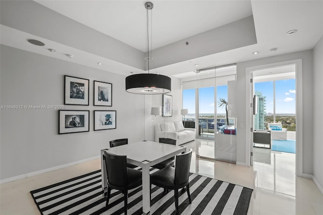 dining area with recessed lighting, a raised ceiling, and baseboards