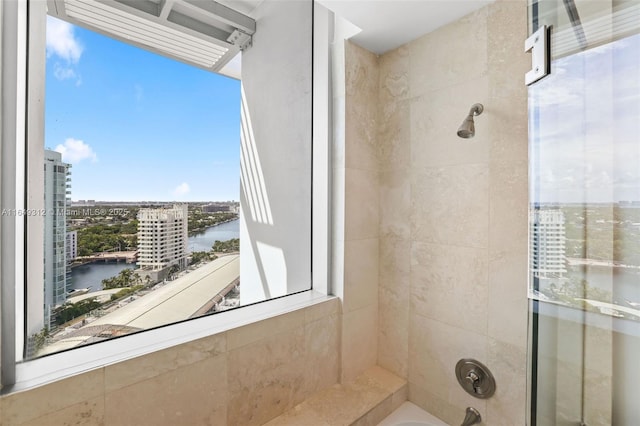 full bath featuring a tub to relax in, a view of city, a water view, and a tile shower