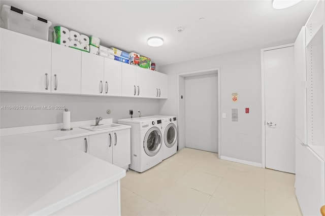 clothes washing area with a sink, cabinet space, and washer and dryer