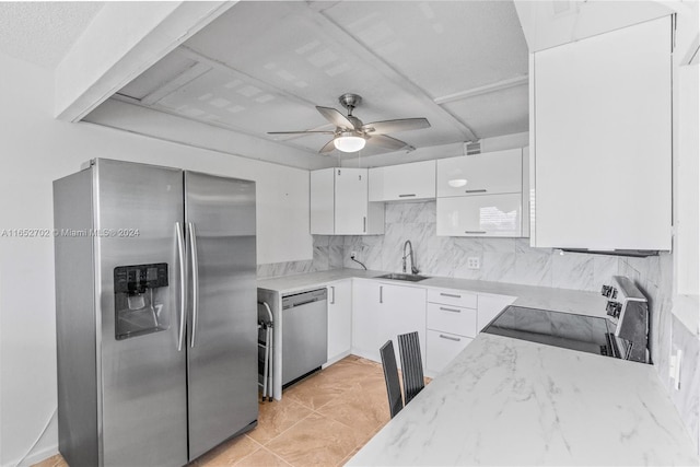 kitchen featuring backsplash, white cabinets, sink, ceiling fan, and stainless steel appliances