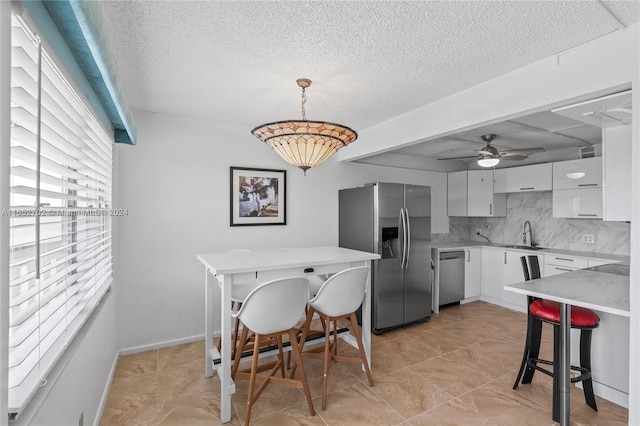 kitchen with a kitchen bar, appliances with stainless steel finishes, backsplash, pendant lighting, and white cabinets