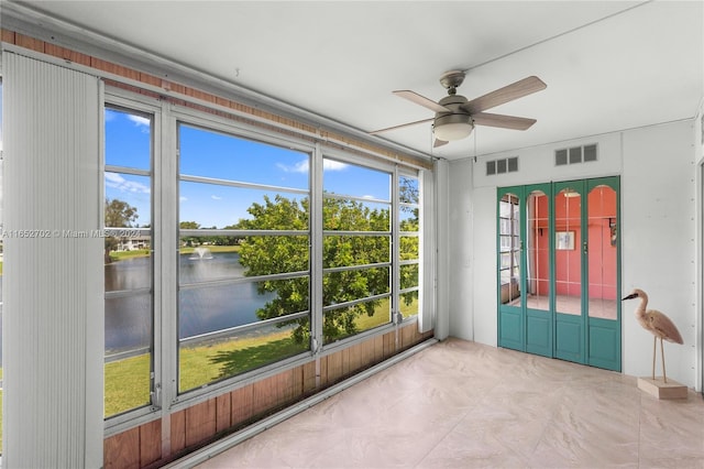 unfurnished sunroom featuring ceiling fan and a water view