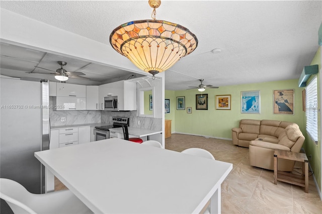 kitchen featuring white cabinets, decorative backsplash, decorative light fixtures, kitchen peninsula, and stainless steel appliances