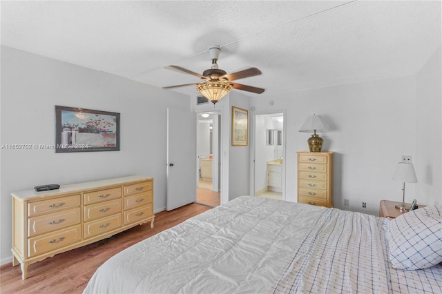 bedroom with connected bathroom, ceiling fan, light hardwood / wood-style floors, and a textured ceiling