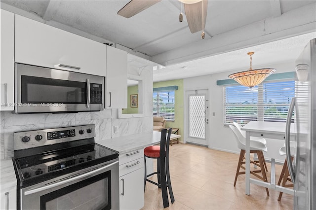 kitchen with appliances with stainless steel finishes, tasteful backsplash, light stone counters, decorative light fixtures, and white cabinetry