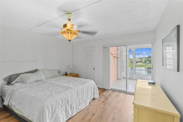 bedroom with access to outside, ceiling fan, a textured ceiling, light hardwood / wood-style floors, and a closet