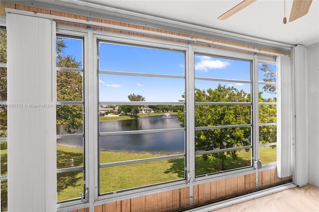 doorway to outside with ceiling fan, a water view, and wood-type flooring