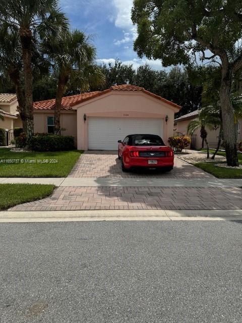 view of front of home featuring a tiled roof, decorative driveway, an attached garage, and stucco siding