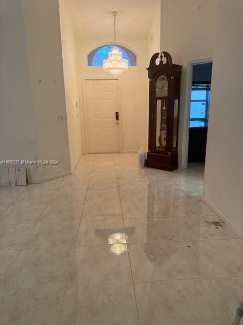 foyer entrance with tile patterned flooring, a notable chandelier, and a towering ceiling