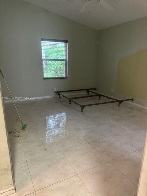 spare room featuring tile patterned flooring, lofted ceiling, baseboards, and ceiling fan